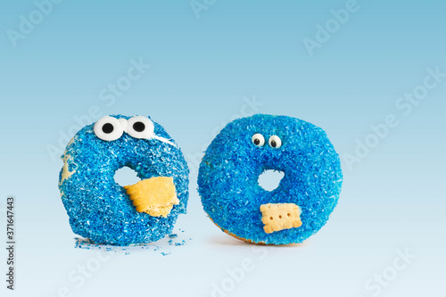 Two Blue donuts with eyes and biscuit against blue Background