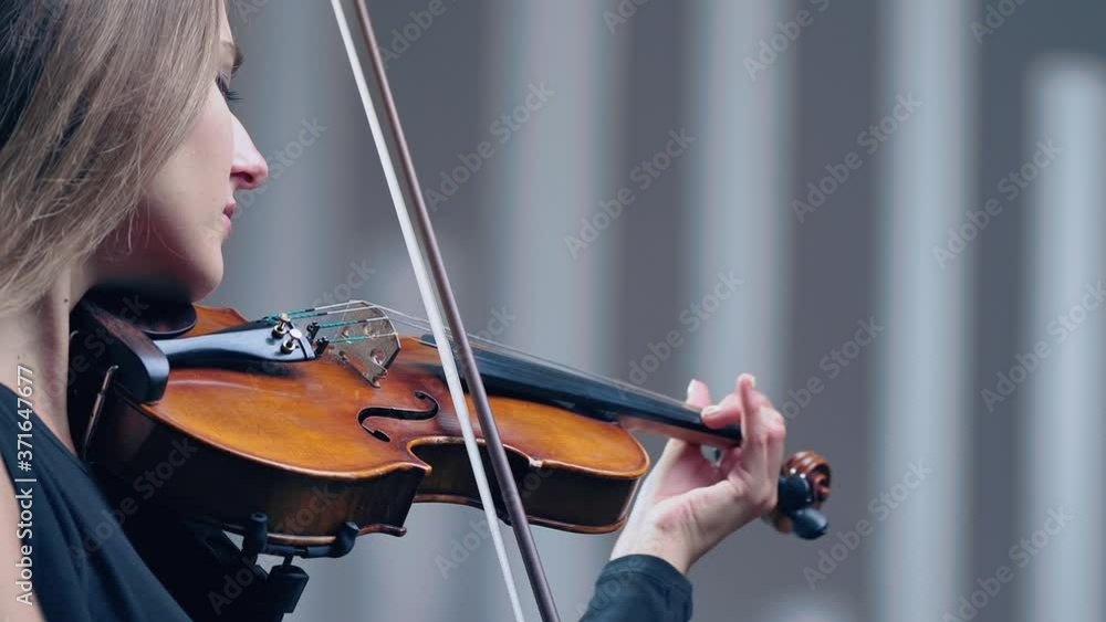 Girl violin playing at studio. Woman is practicing playing musical instrument