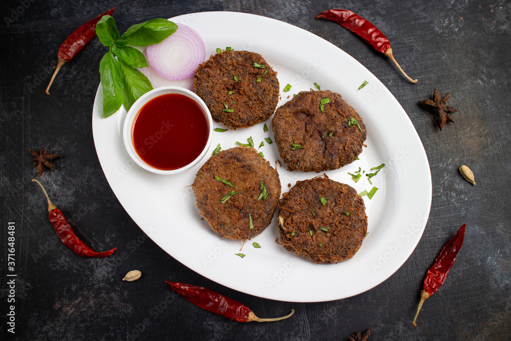 Many beef or chicken cutlet, tomato sauce Kerala South India. hot and spicy tea time snack on white plate, dark black background. fried meat of veal, mutton or fish. Top view Indian snack non veg food Many beef or chicken cutlet, tomato sauce Kerala South India. hot and spicy tea time snack on white plate, dark black background. fried meat of veal, mutton or fish. Top view Indian snack non veg food