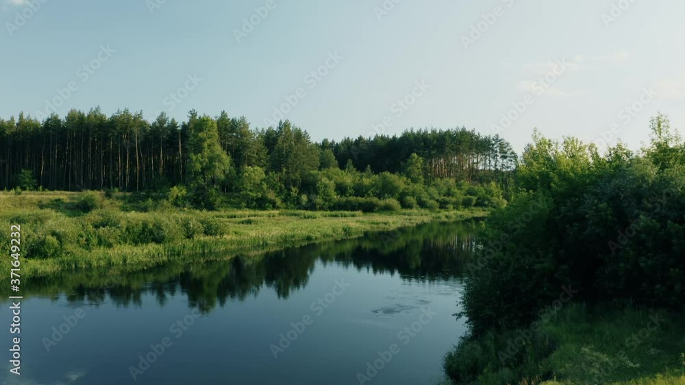 Drone Flight View Above Calm River Surface. Green Forest Woods Landscape In Sunny Summer Evening. Top View Of Beautiful European Nature From High Attitude. Drone View. Bird's Eye View 4K Drone Flight View Above Calm River Surface. Green Forest Woods Landscape In Sunny Summer Evening. Top View Of Beautiful European Nature From High Attitude. Drone View. Bird's Eye View 4K