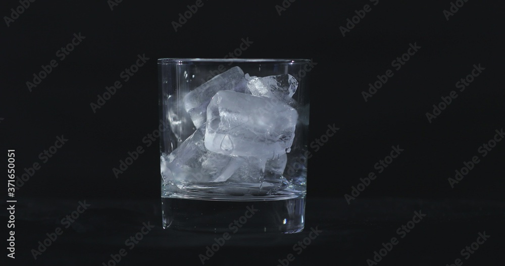 Ice cubes melt in the alcohol, whiskey glass and smoke is floating against a black background Ice cubes melt in the alcohol, whiskey glass and smoke is floating against a black background