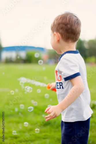 little boy playing with soap bubbles. summer street games in the park.