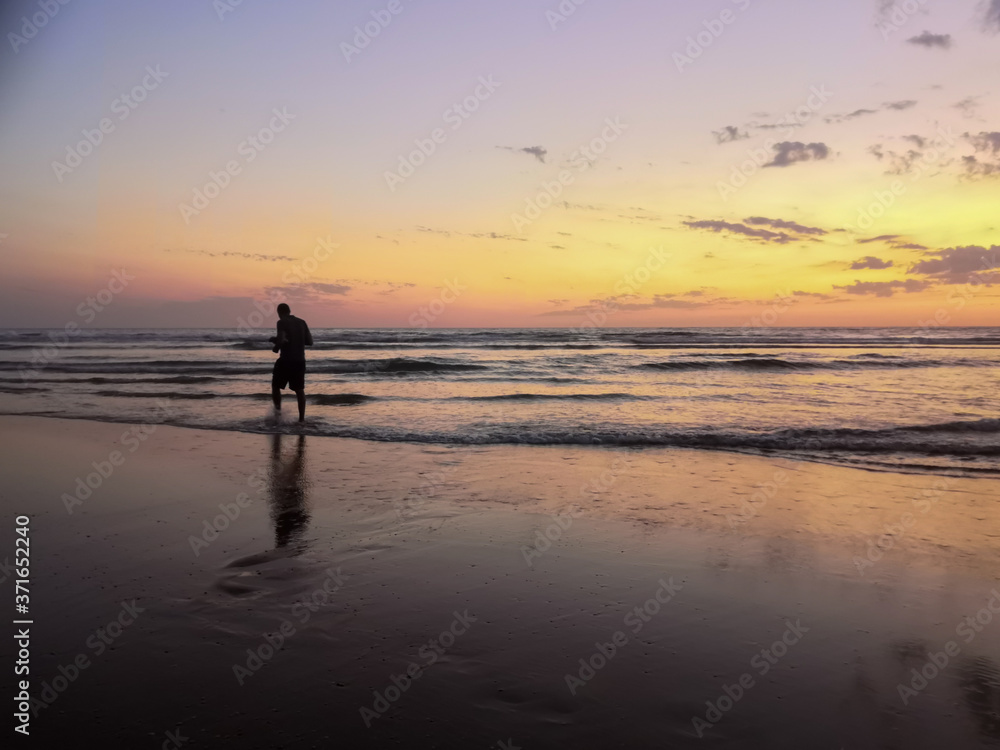 
Silhouette of a man by the ocean at sunset