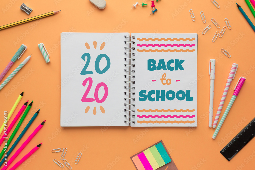 Stock photo of back to school with an open notebook with lettering and some stationery objects on a salmon background Stock photo of back to school with an open notebook with lettering and some stationery objects on a salmon background