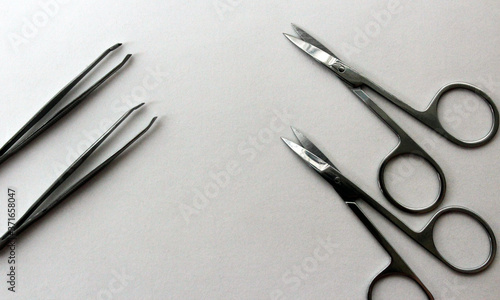 White background with nail scissors and with metal cosmetic tongs