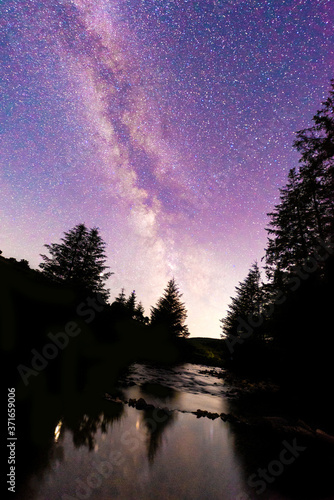 Milky way over silhouettes of trees & reflection in stream © Arthur Cauty