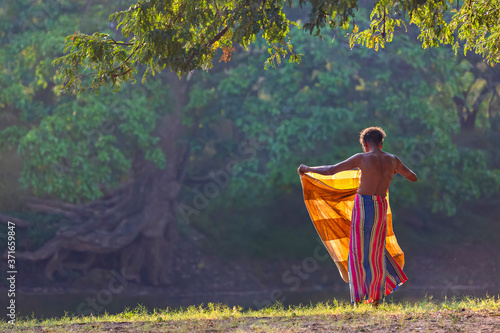 Local man folding his sarong after bathing at the sunset, Kataragama, Sri Lanka