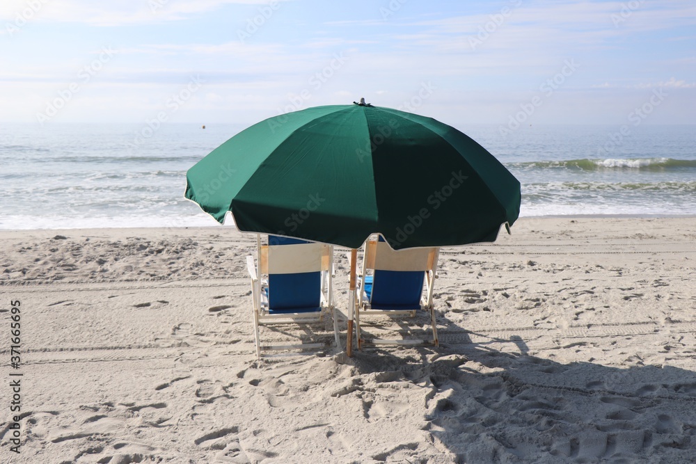 Umbrella and lounging chairs on the beach facing the ocean Umbrella and lounging chairs on the beach facing the ocean