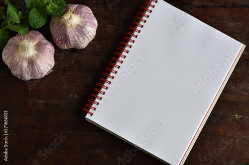 caderno de receitas em branco ao lado de temperos , cebola, alho e alecrim photo