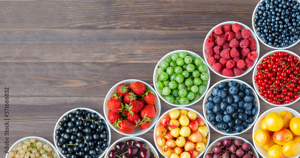 A set of berries in the round plates. Brown wooden background. Copy space. A set of berries in the round plates. Brown wooden background. Copy space.