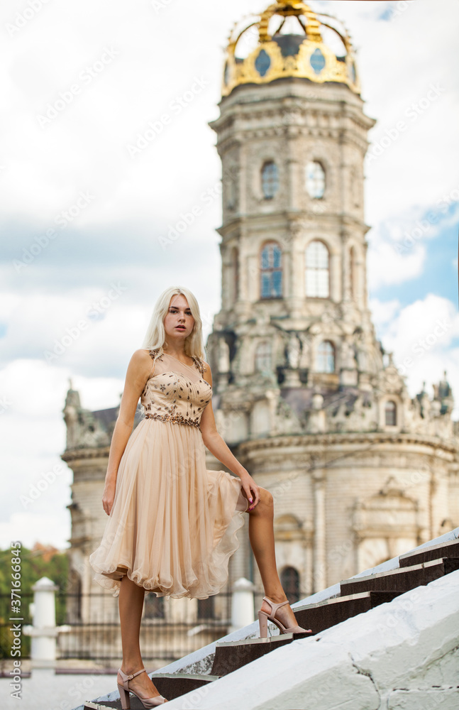 Fototapeta premium Portrait of a young girl in beige dress against the background of the Temple
