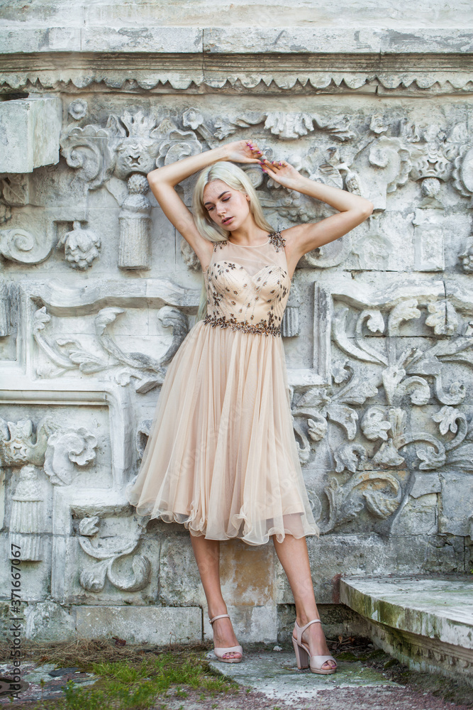 Young beautiful blonde girl in beige dress