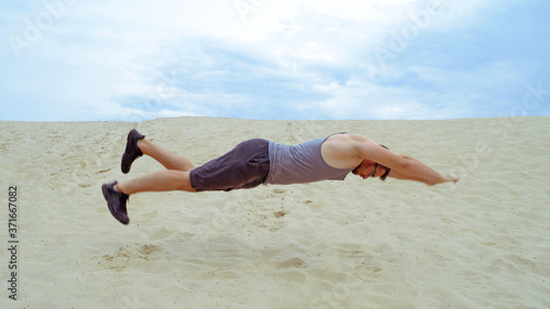 Young sporty man jumping on the sand in the desert