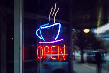 Neon open sign with coffee cup  shot through dirty glass door