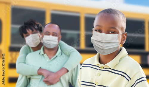 Young African American Student and Parents Near School Bus Wearing Medical Face Masks During Coronavirus Pandemic