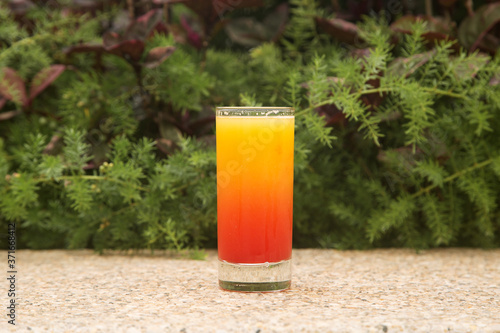 glass of orange juice with syrup in a glass on a green background