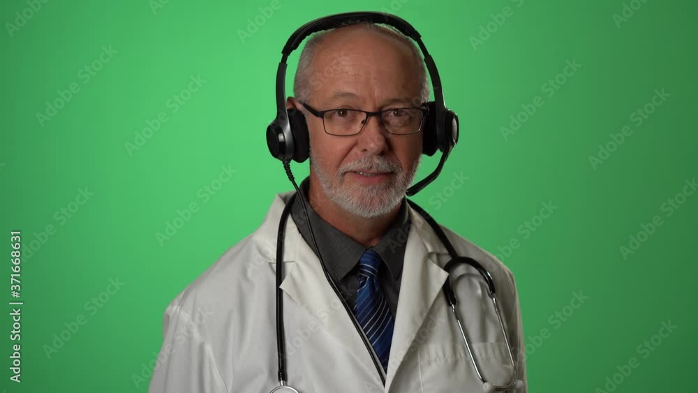 Portrait of male doctor wearing a lab coat and headset with microphone giving medical advice consulting with a patient via a video conferencing call on green screen. Portrait of male doctor wearing a lab coat and headset with microphone giving medical advice consulting with a patient via a video conferencing call on green screen.