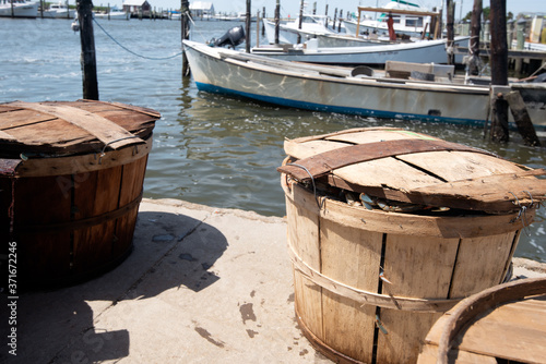 Bild auf Leinwand Bushel baskets full of blue crabs sit on a dock on the Chesapeake Bay with boats in the background