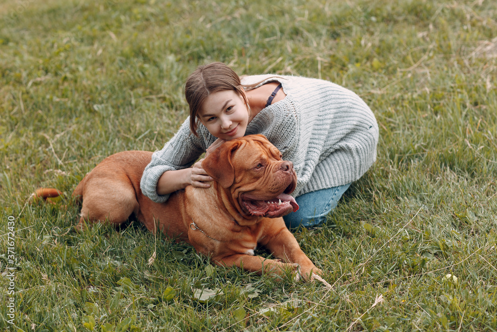 Dogue de Bordeaux or French Mastiff with young woman at outdoor park meadow. Dogue de Bordeaux or French Mastiff with young woman at outdoor park meadow.