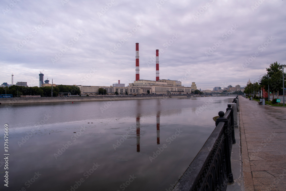 a factory on the river embankment with large striped pipes
