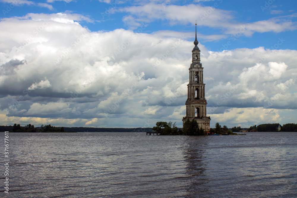 a flooded old bell tower in the middle of a river against a cloudy dramatic sky and a space to copy in Kalyazin Russia