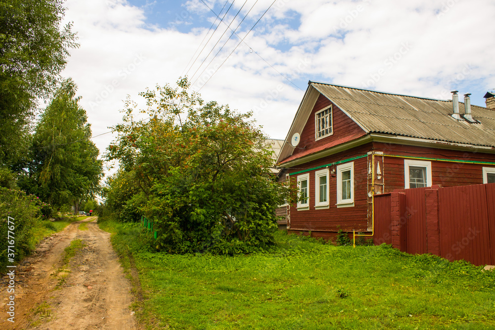 a street with old wooden Russian huts and green trees on a summer day and space for copying in Kalyazin Russia
