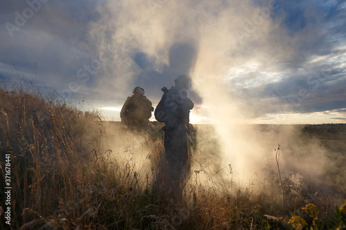 silhouettes of soldiers in the smoke against the sunset sky © artem