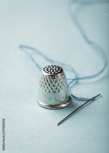 Slika na platnu Vintage silver metal thimble and needle on blue background