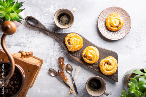 Fresh pastry sweet swirl buns with raisins on wooden board for breakfast or brunch and coffee. Party food concept. Top view. © Iryna Melnyk