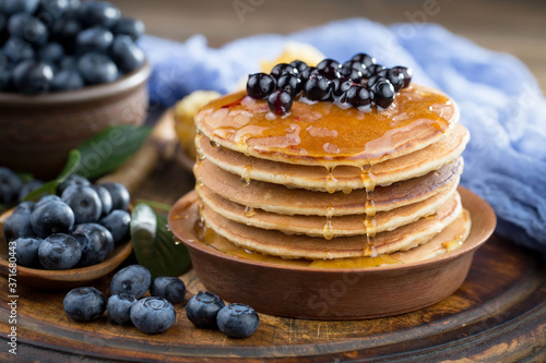 Blueberries in a plate and pancakes, on an old background.