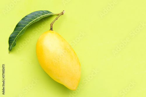 Top view of yellow mango on green background.