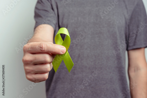 Man showing turquoise or teal ribbon. Awareness ribbon.