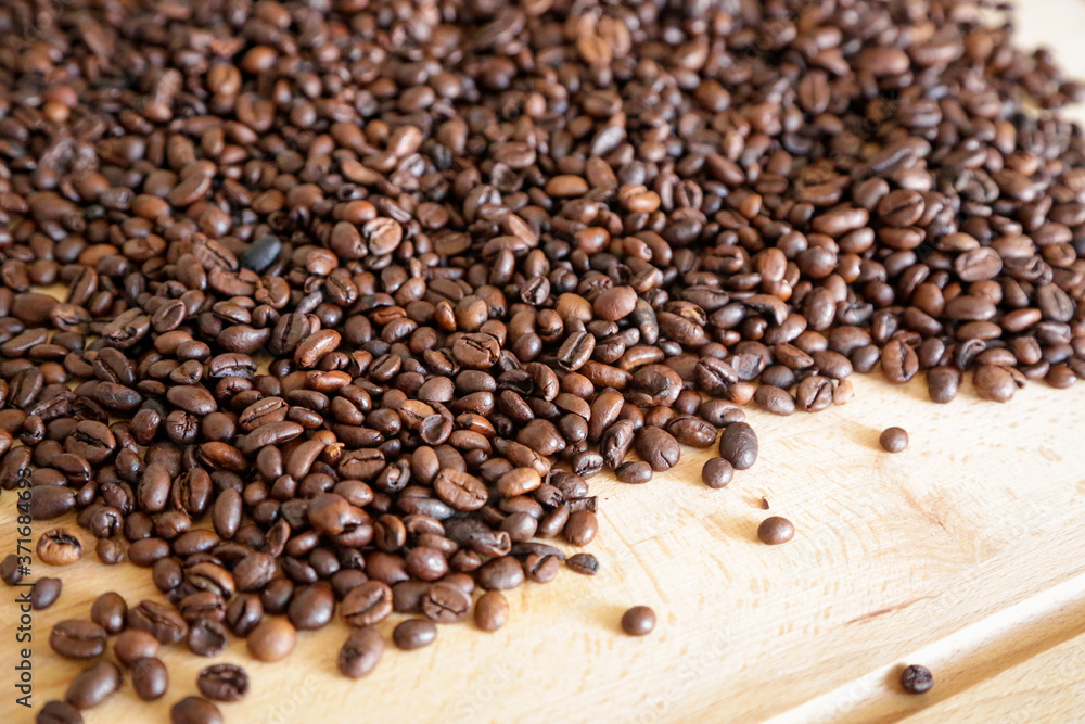 Fototapeta premium Coffee grains on wooden table, with natural light