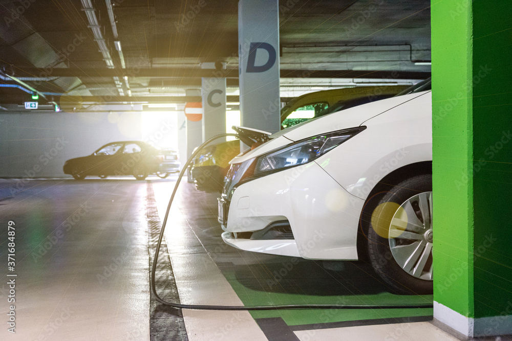 Fototapeta premium Eco friendly car. Hybrid vehicle - green technology of future. Electric car charge battery on eco energy charger station. Clean energy future of transportation ecology concept.