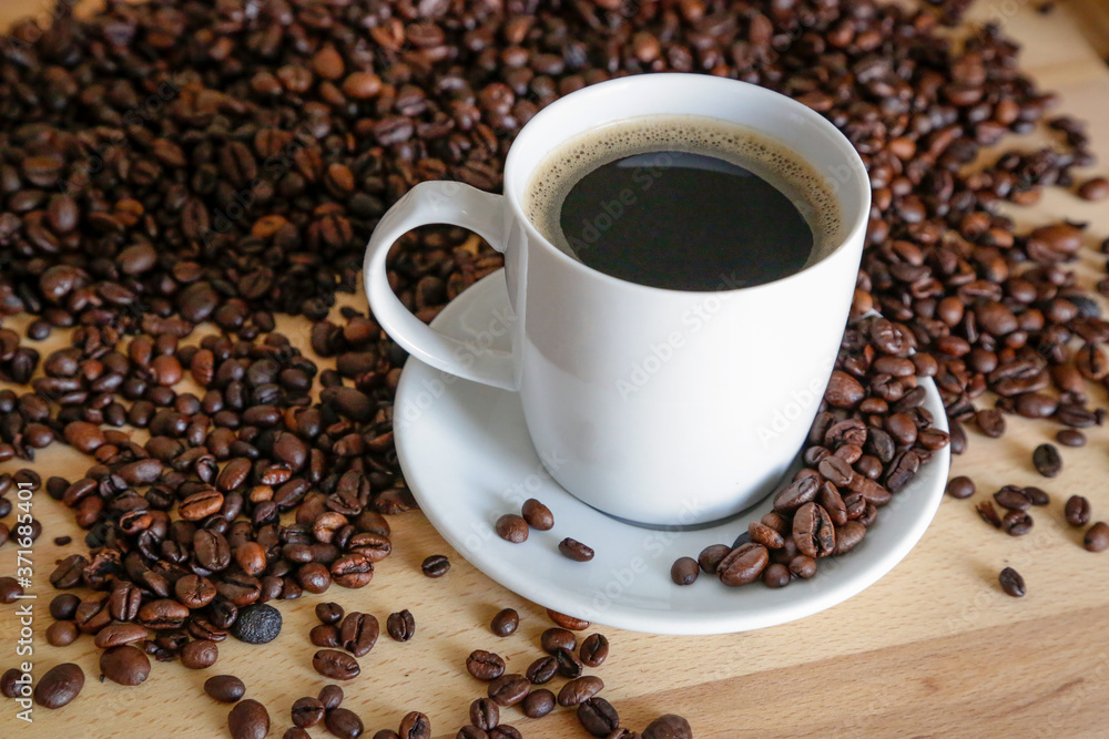 A cup of black coffee with coffee grains, natural light on wooden table A cup of black coffee with coffee grains, natural light on wooden table