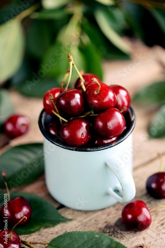 Fresh ripe organic sweet cherries in a vintage cup on an old wooden background. photo