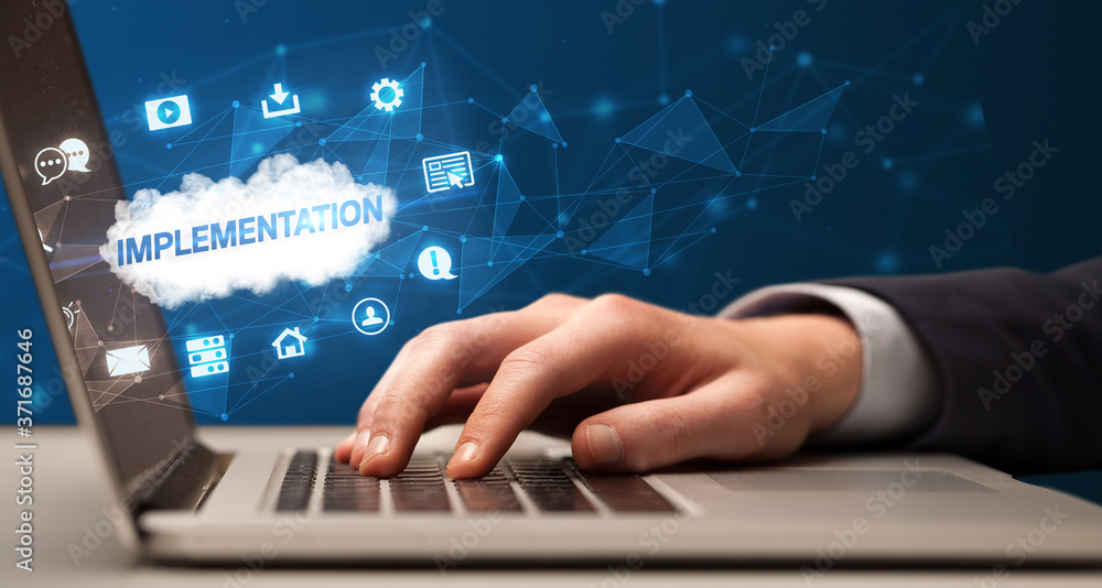 Businessman working on laptop with IMPLEMENTATION inscription, modern technology concept Businessman working on laptop with IMPLEMENTATION inscription, modern technology concept