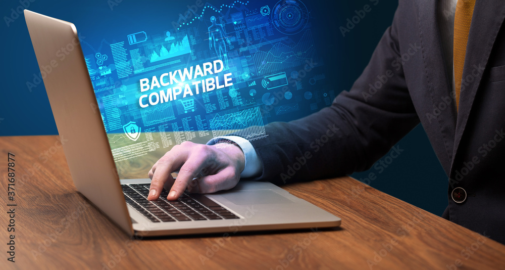 Businessman working on laptop with BACKWARD COMPATIBLE inscription, cyber technology concept Businessman working on laptop with BACKWARD COMPATIBLE inscription, cyber technology concept