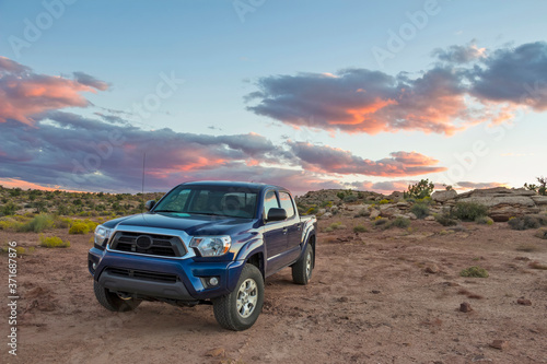 A truck with emblems removed parked in the wilderness of the Utah Desert at sunset.