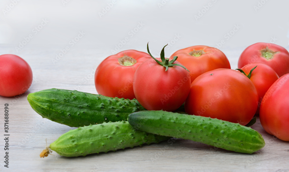 Fresh tomatoes and cucumbers on a light background
