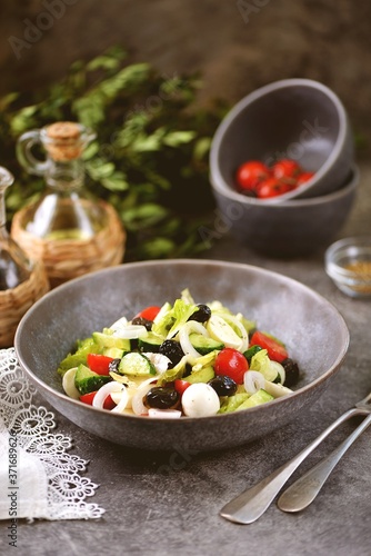 Greek salad with mozzarella. Salad with bell peppers, cherry tomatoes, cucumbers, feta, oregano, olives, onions, olive oil and lemon juice.