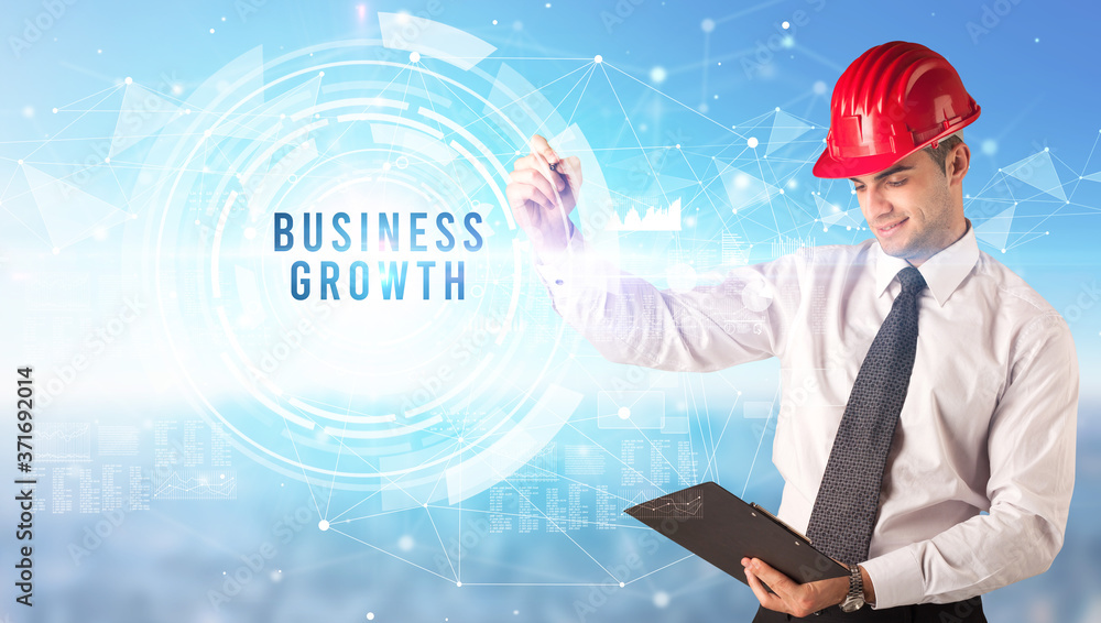 Handsome businessman with helmet drawing BUSINESS GROWTH inscription, contruction business concept Handsome businessman with helmet drawing BUSINESS GROWTH inscription, contruction business concept