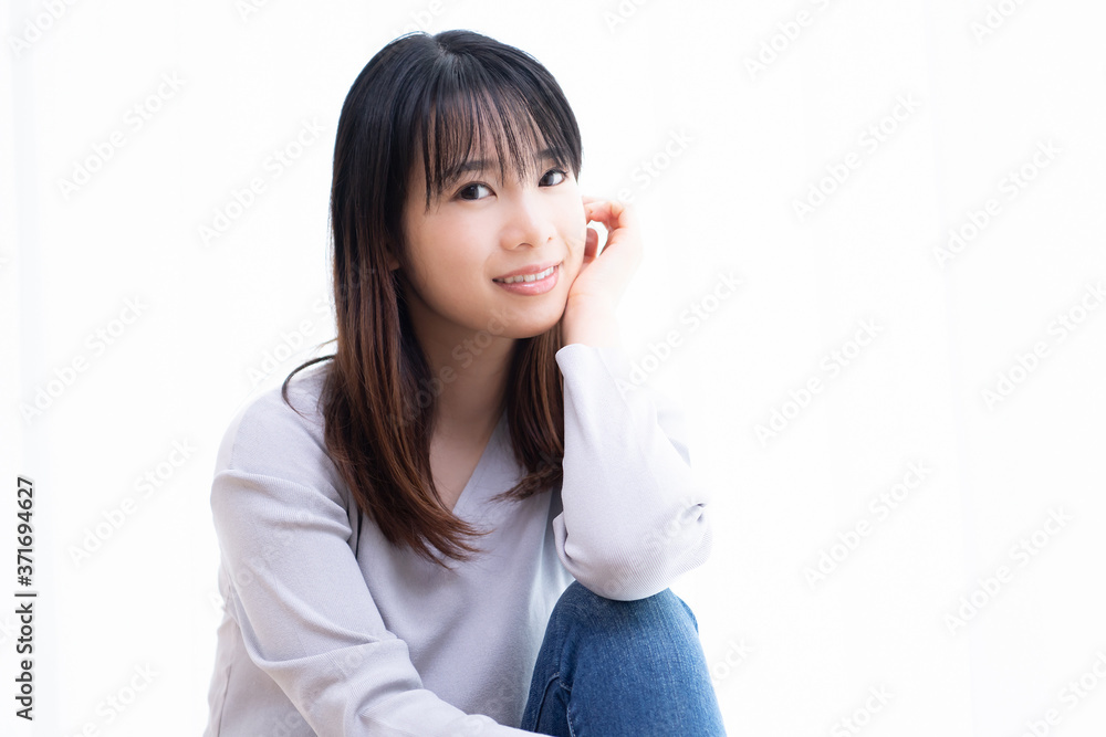 部屋の窓際に座る若い女性 部屋の窓際に座る若い女性