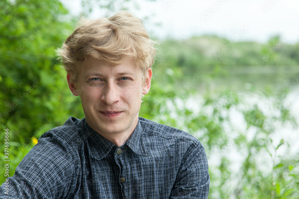 Closeup portrait of young blonde guy in blue shirt in autumn park Closeup portrait of young blonde guy in blue shirt in autumn park