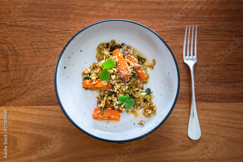 Grain salad with freekeh, roasted carrots and orange dressing, sprinkled with hazelnuts and coriander or cilantro, flat lay