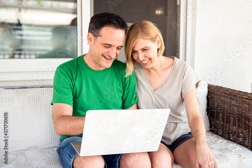 Middle Aged Couple Using Laptop Computer at Home at the Balcony.