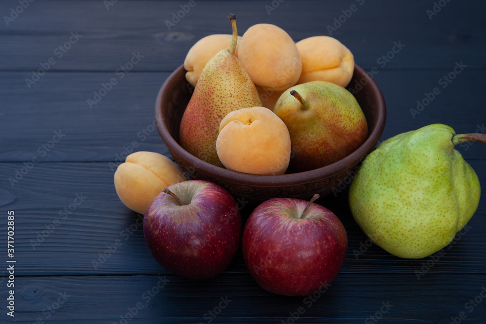 Apricots, pears and apples on a dark wooden background. Apricots, pears and apples on a dark wooden background.