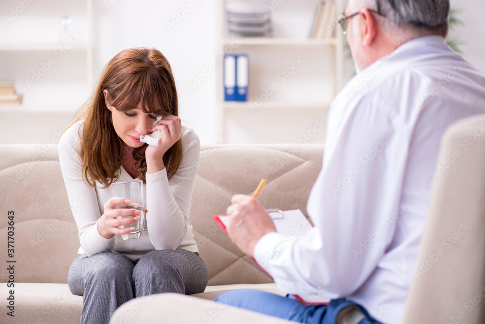 Fototapeta premium Young woman visiting old male doctor psychologist