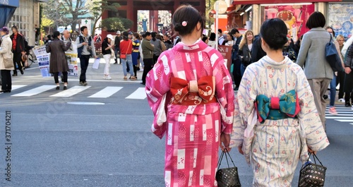 Two young women are dressed in a traditional kimono as they walk down a street in Japan