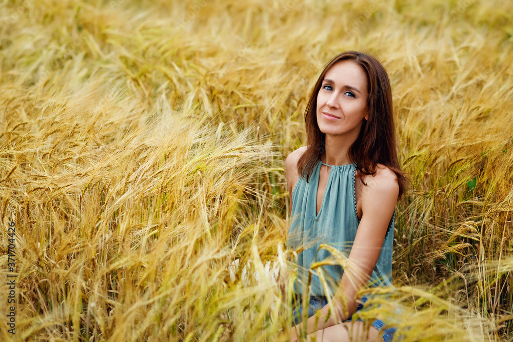 Close up portrait of a happy smiling woman with long hair sitting in a wheat field Close up portrait of a happy smiling woman with long hair sitting in a wheat field